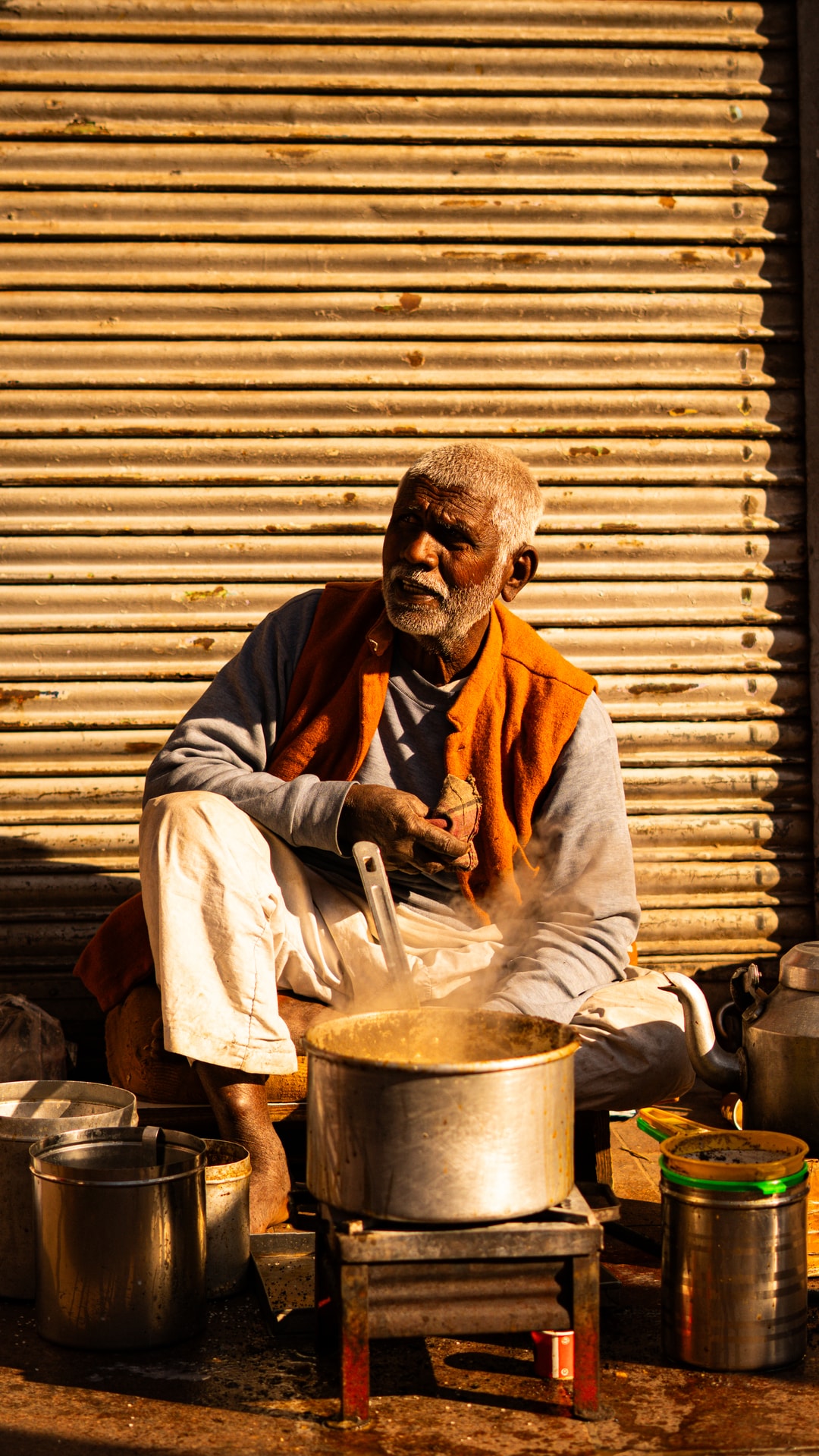 Old man cooking in front of metal shutters